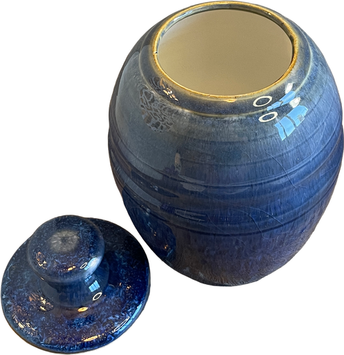 A blue glazed ceramic jar with its matching lid placed in front, set against a plain white background.