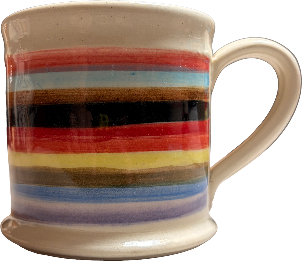 A ceramic mug with a cream-colored glaze and horizontal painted stripes in red, light blue, brown, black, yellow, and purple, shown against a plain white background.