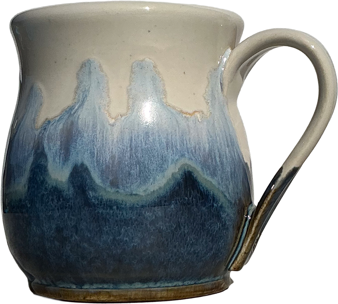 A handmade ceramic mug with a cream-colored glazed top and handle, featuring a dripping blue and navy blue glaze pattern resembling waves or mountains, with a brown clay showing at the base.